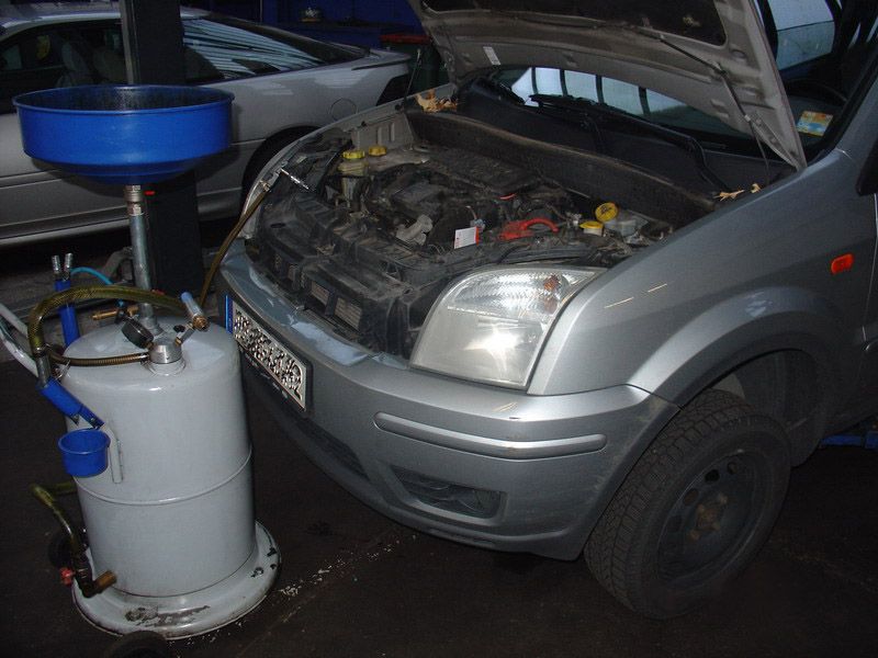 Ein silbernes Auto mit geöffneter Motorhaube wird gewartet