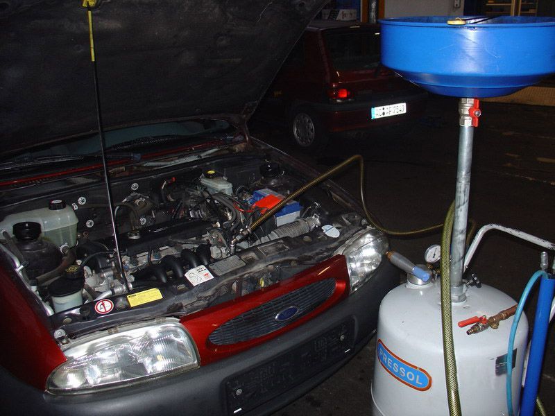 An einem Ford wird mit geöffneter Motorhaube gearbeitet