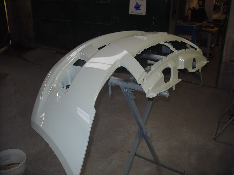 Eine weiße Autostoßstange steht auf einem Ständer in einer Garage