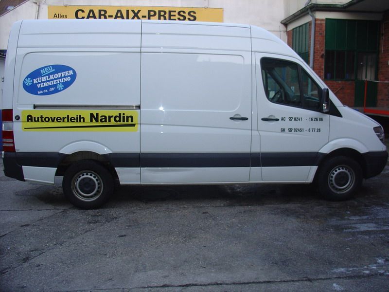Ein weißer Lieferwagen steht vor einem gelben Schild mit der Aufschrift „Car-Aix-Press“