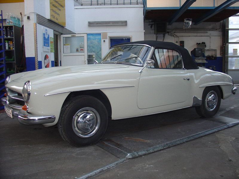 Ein weißes Auto mit schwarzem Dach steht in einer Garage