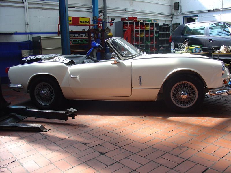 Ein weißes Auto steht in einer Garage mit einem Schild mit der Aufschrift „tna“ darauf