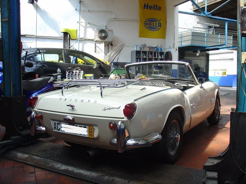 Ein weißes Auto steht vor einem gelben Schild mit der Aufschrift „Hella“