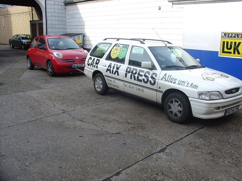 Ein weißes Auto mit der Aufschrift „Car AUX Press“ auf der Seite