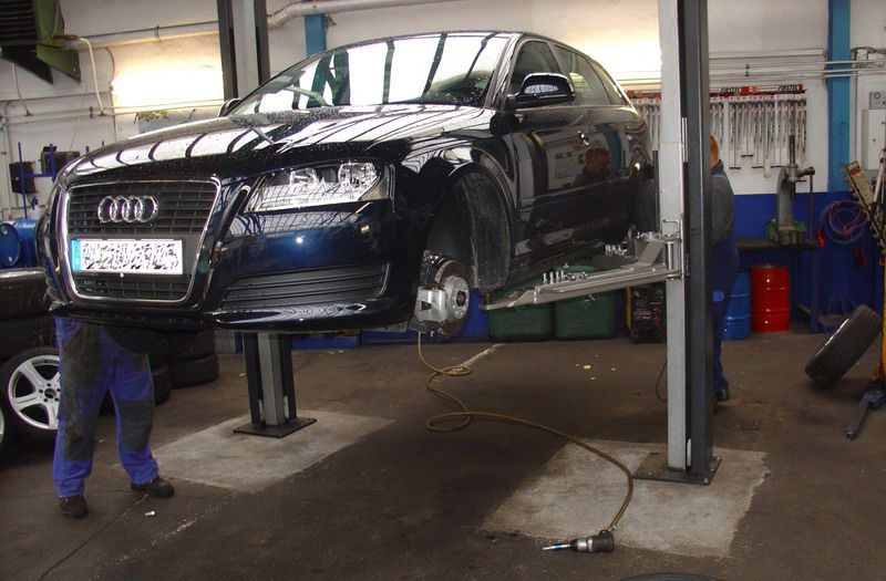 Ein blauer Audi steht auf einer Hebebühne in einer Garage