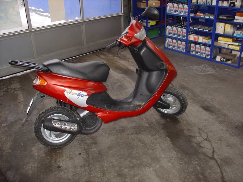 Ein rot-schwarzer Roller steht in einer Garage