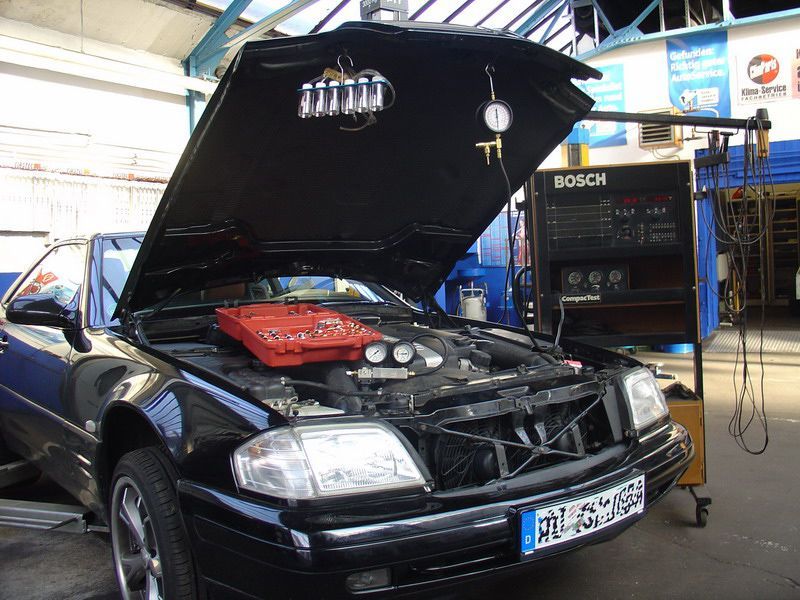 Ein schwarzes Auto mit geöffneter Motorhaube wird von Bosch bearbeitet