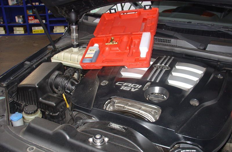 Ein schwarzes Auto mit geöffneter Motorhaube und einem Werkzeugkasten auf dem Motor