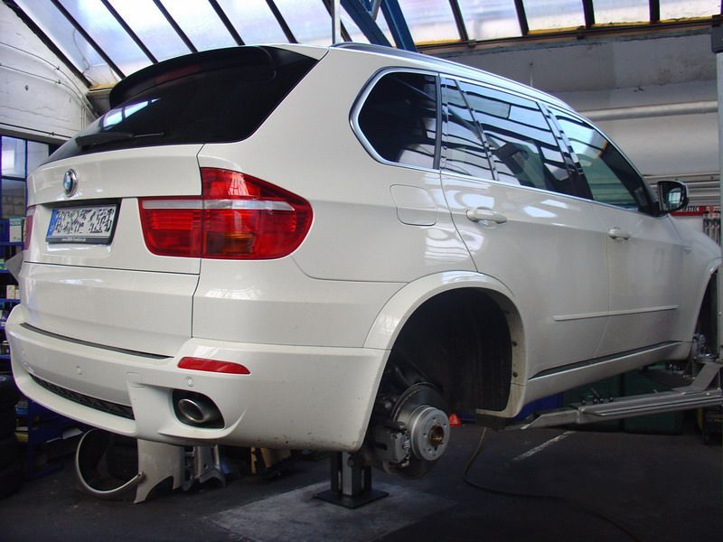 Ein weißer BMW steht auf einer Hebebühne in einer Garage