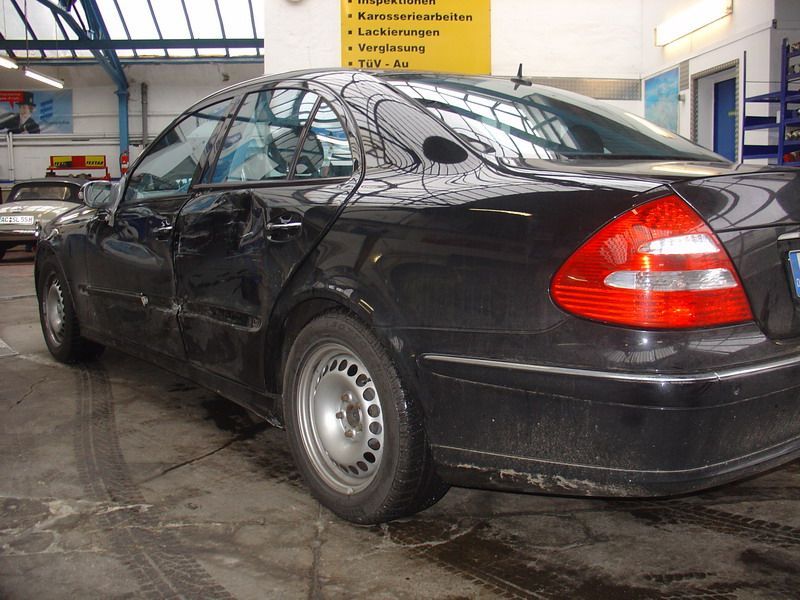 Ein schwarzes Auto steht in einer Garage mit einem gelben Schild dahinter