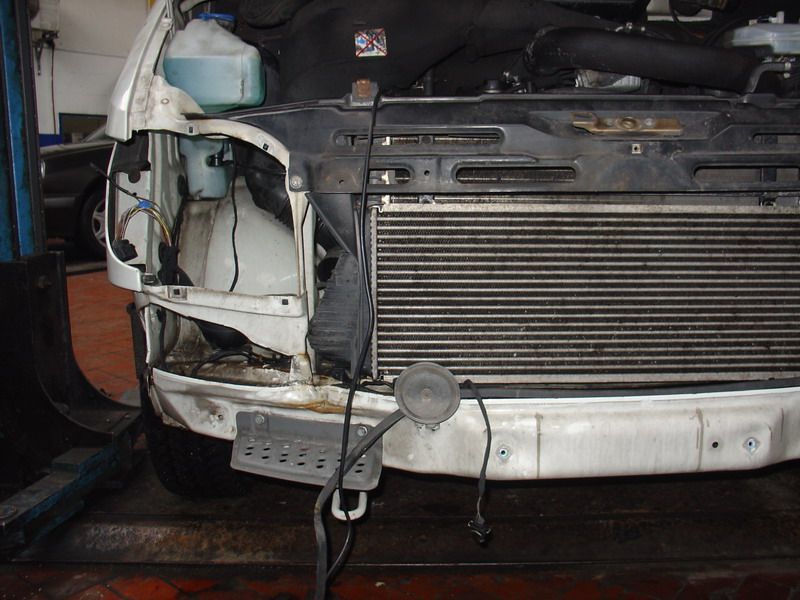 An einem Auto mit ausgebautem Kühler ist eine Hupe angebracht