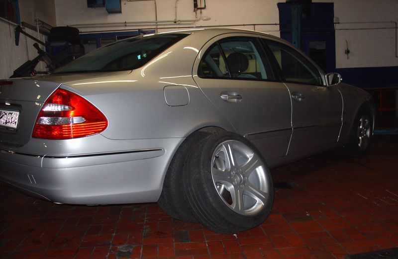 Ein silbernes Auto steht in einer Garage mit einem Reifen auf dem Boden