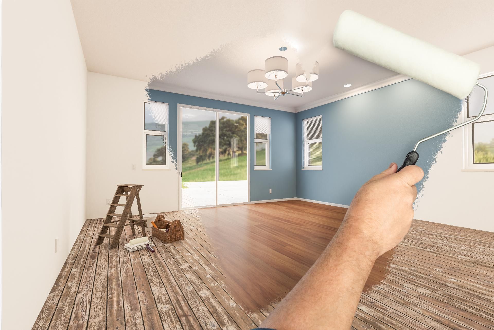 Eine blaue Wand wurde von Hand in einem leeren Raum mit Holzboden und Kronleuchter gestrichen.
