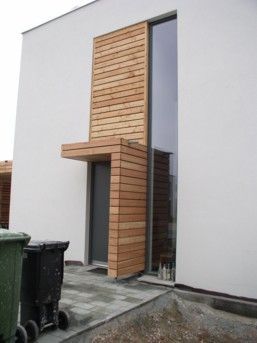 Moderner Hauseingang mit Holzverkleidung um die Tür, hohes Fenster. 