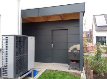 Wärmepumpenanlage neben einem dunkelgrauen Schuppen.