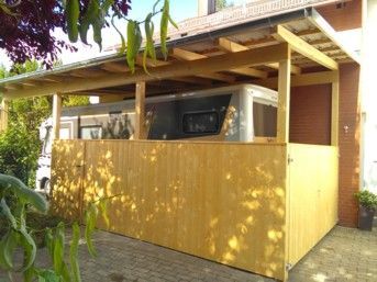Eine Holzkonstruktion schützt ein silbernes Wohnmobil. 