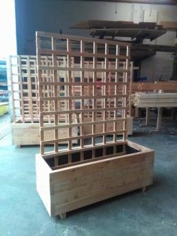 Pflanzkästen aus Holz mit Rankgitter im Hintergrund.