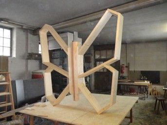 Unbehandeltes, schmetterlingsförmiges Holzregal auf einer Werkbank in einer Werkstatt.