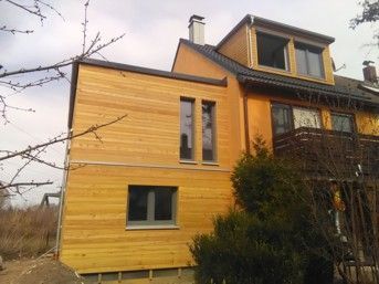 Ein Haus mit Holzverkleidung an einem neuen Anbau.