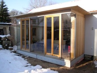 Wintergartenanbau mit großen Glasfenstern und Holzrahmen.