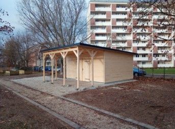Holzgebäude mit überdachter Veranda, Kiesweg.