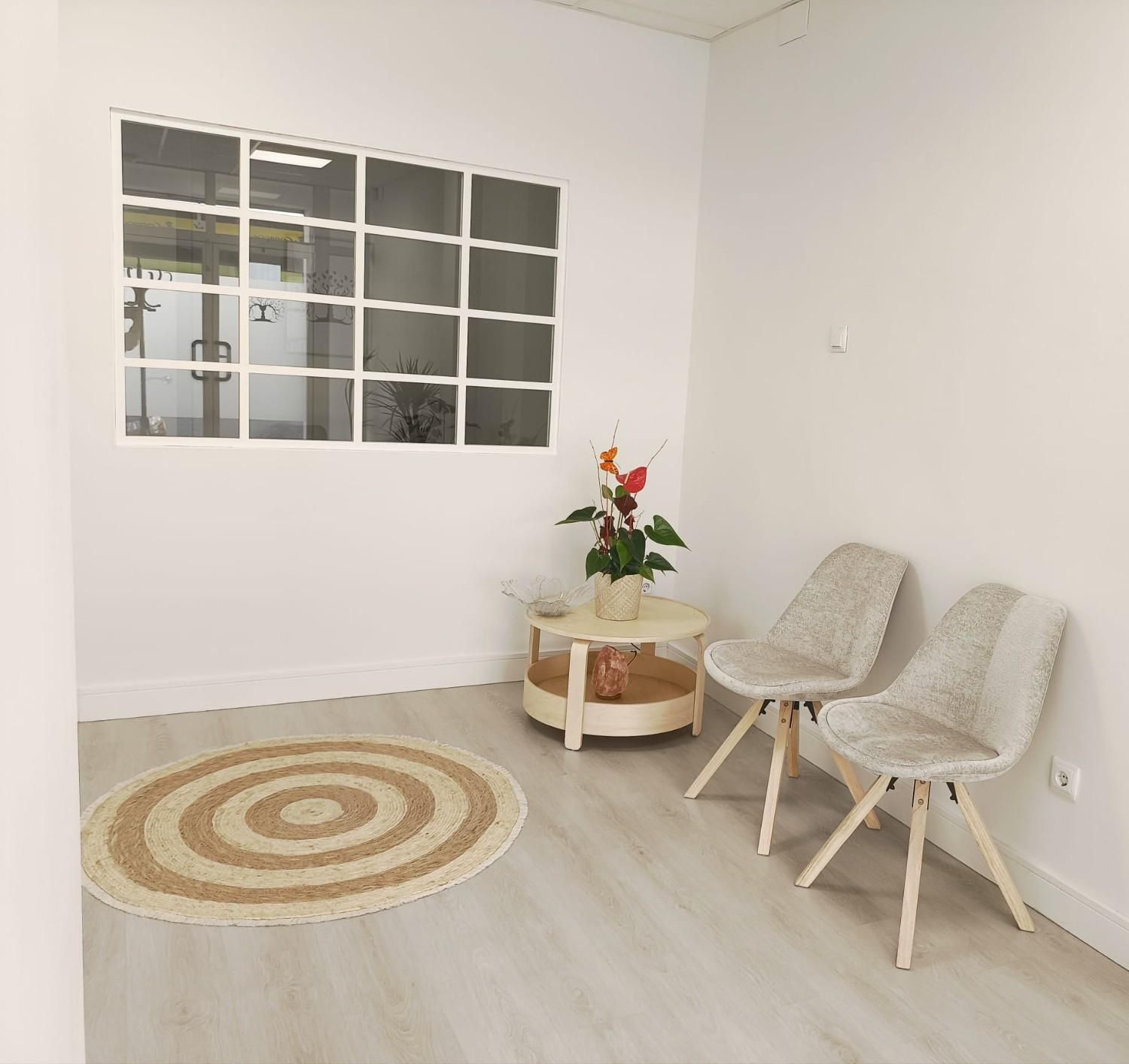 Una sala de espera minimalista con dos sillas tapizadas, una mesa de centro 