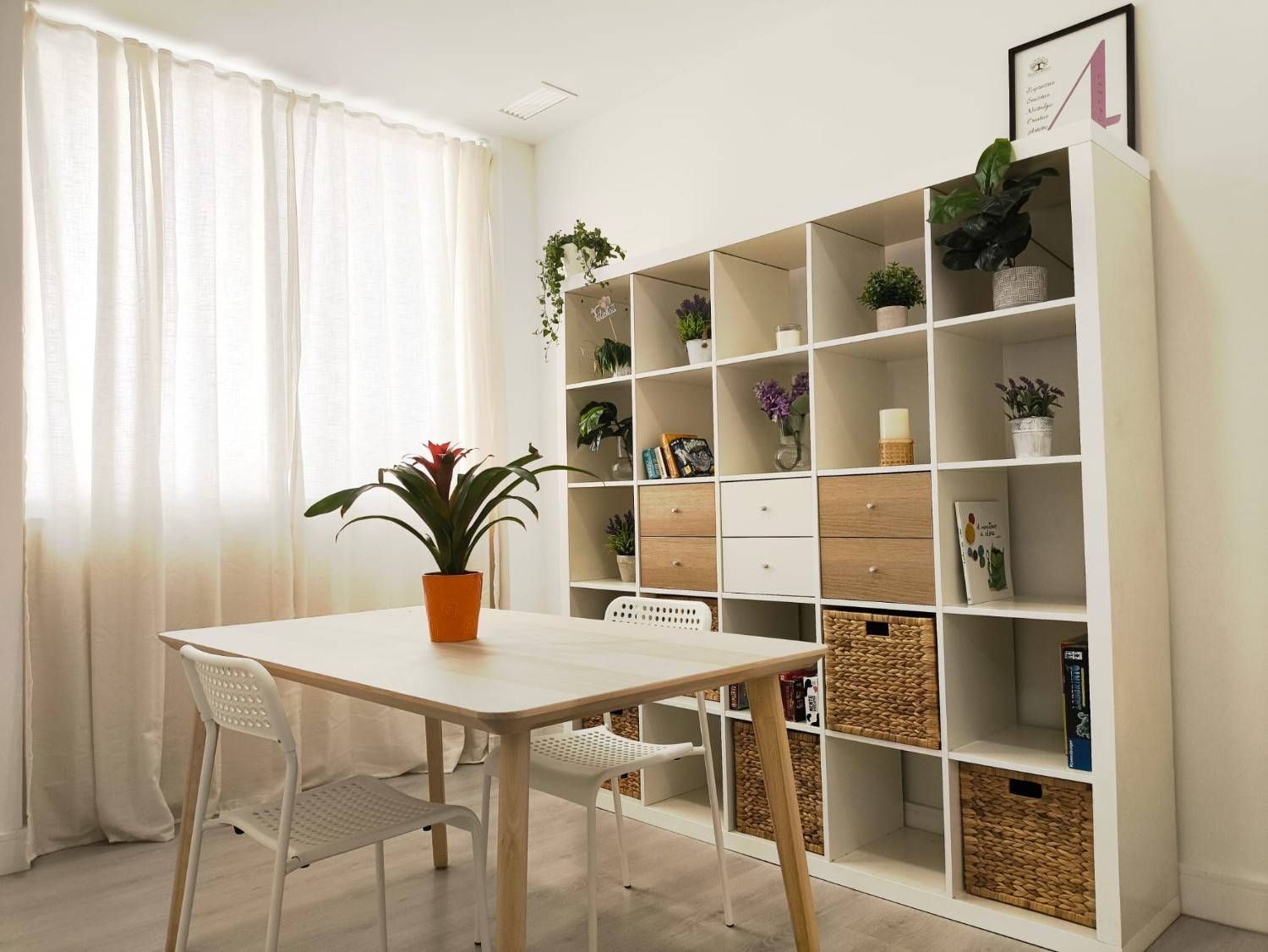 En una habitación luminosa, junto a una gran estantería blanca con rejilla,