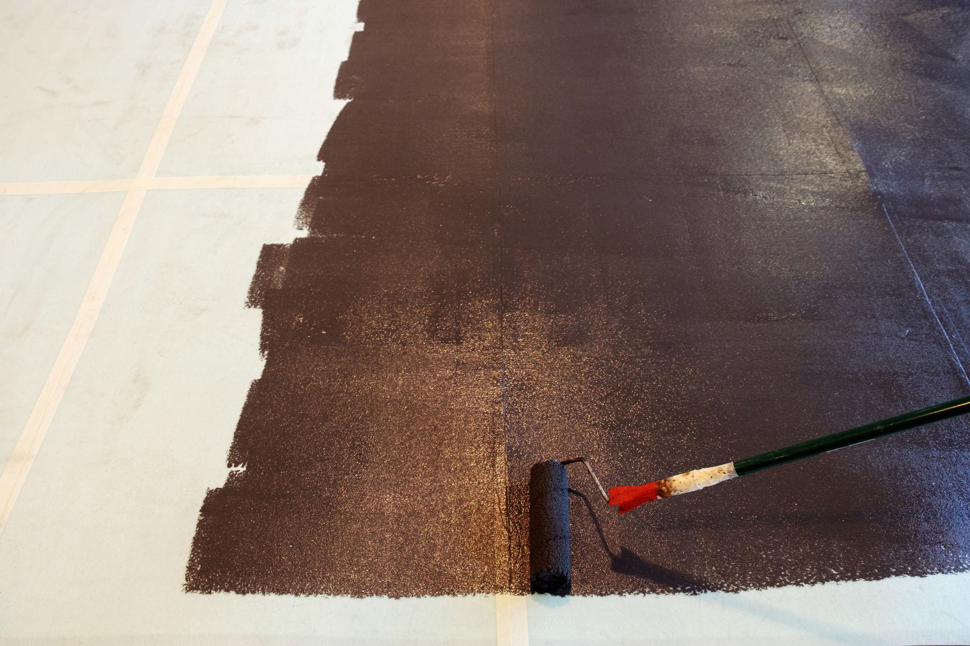 Una persona está pintando un piso con un rodillo.