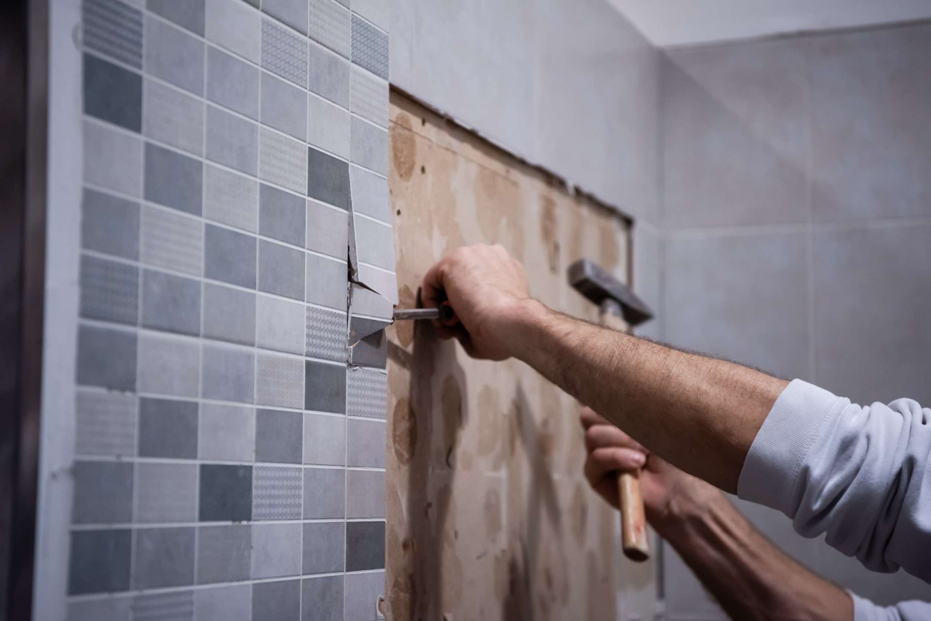 Un hombre está clavando un clavo en una pared de azulejos.