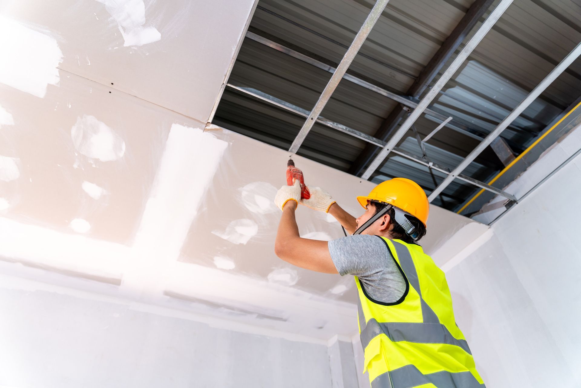 Un trabajador de la construcción está trabajando en un techo con un taladro.