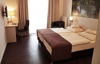 Ein gemütliches Hotelzimmer mit Doppelbett, Schreibtisch, Stuhl und sanfter Beleuchtung.