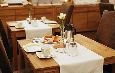 Decken Sie den Esstisch in einem gemütlichen Restaurant mit weißen Tischläufern, Tassen, Tellern, Brot und Kaffeekaraffen.