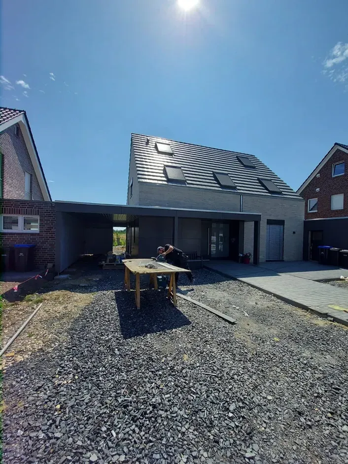 Ein Mann steht vor einem Haus, davor steht ein Tisch.