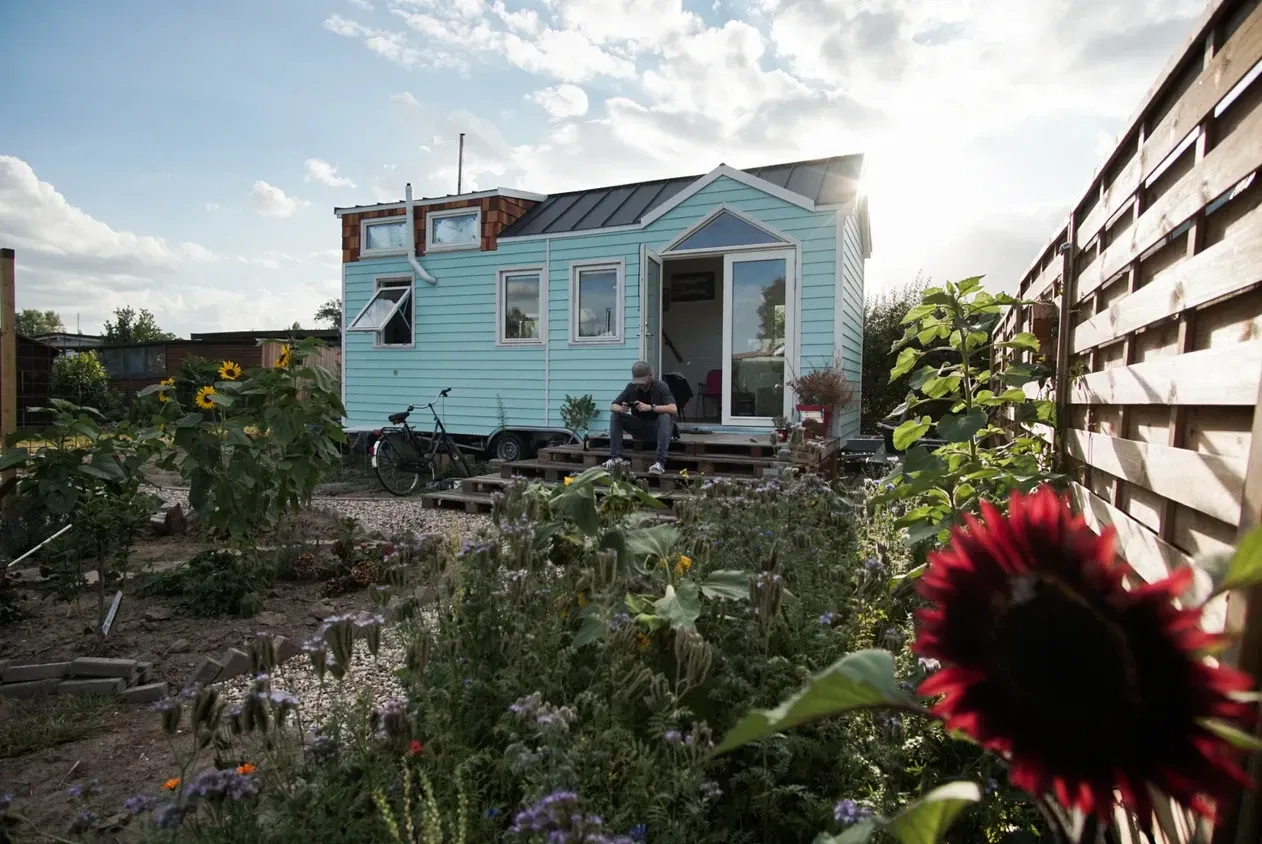Ein Mann sitzt auf der Veranda eines kleinen Hauses.