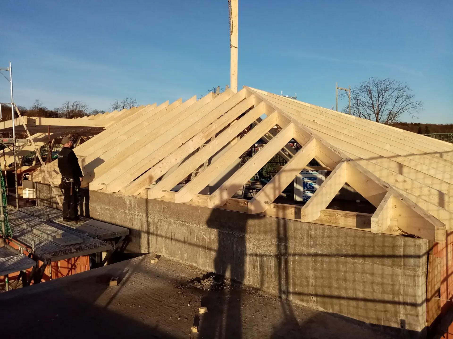Ein Mann steht auf einem im Bau befindlichen Holzdach.