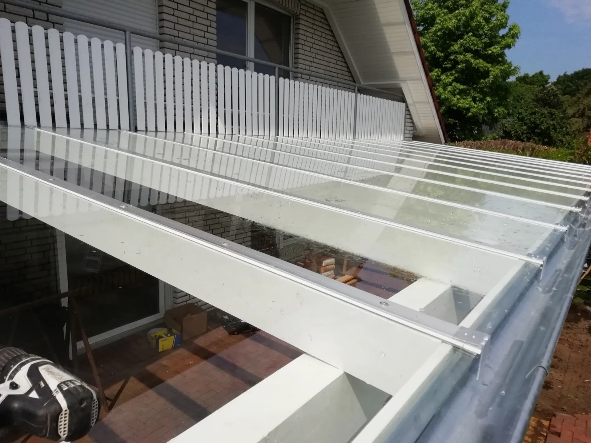 Ein Balkon mit Glasdach und weißem Geländer.