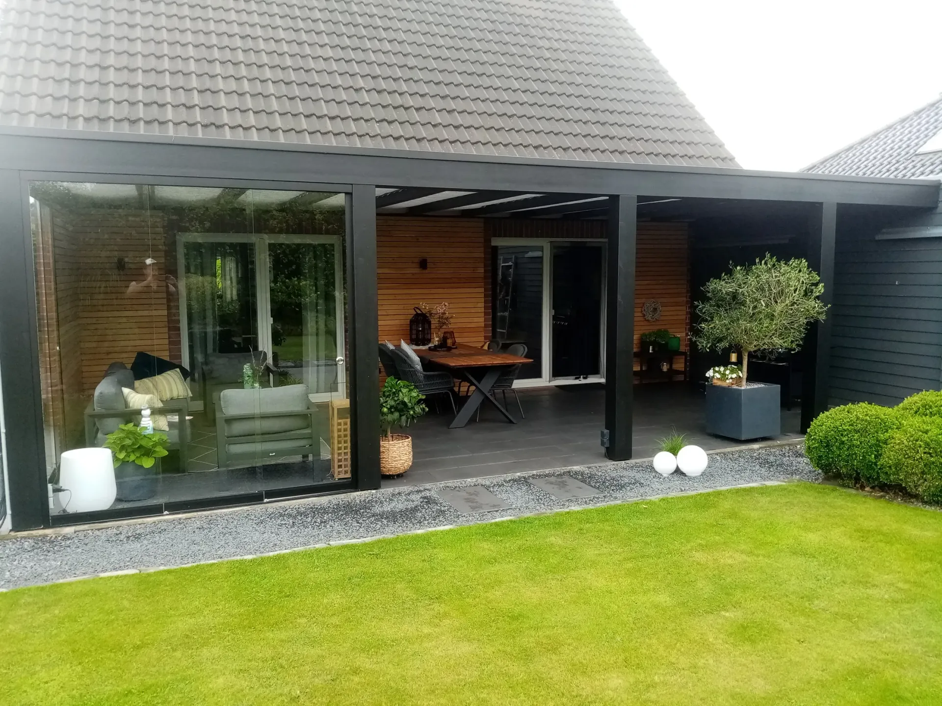 Vor einem Haus gibt es eine Terrasse mit Tisch und Stühlen.