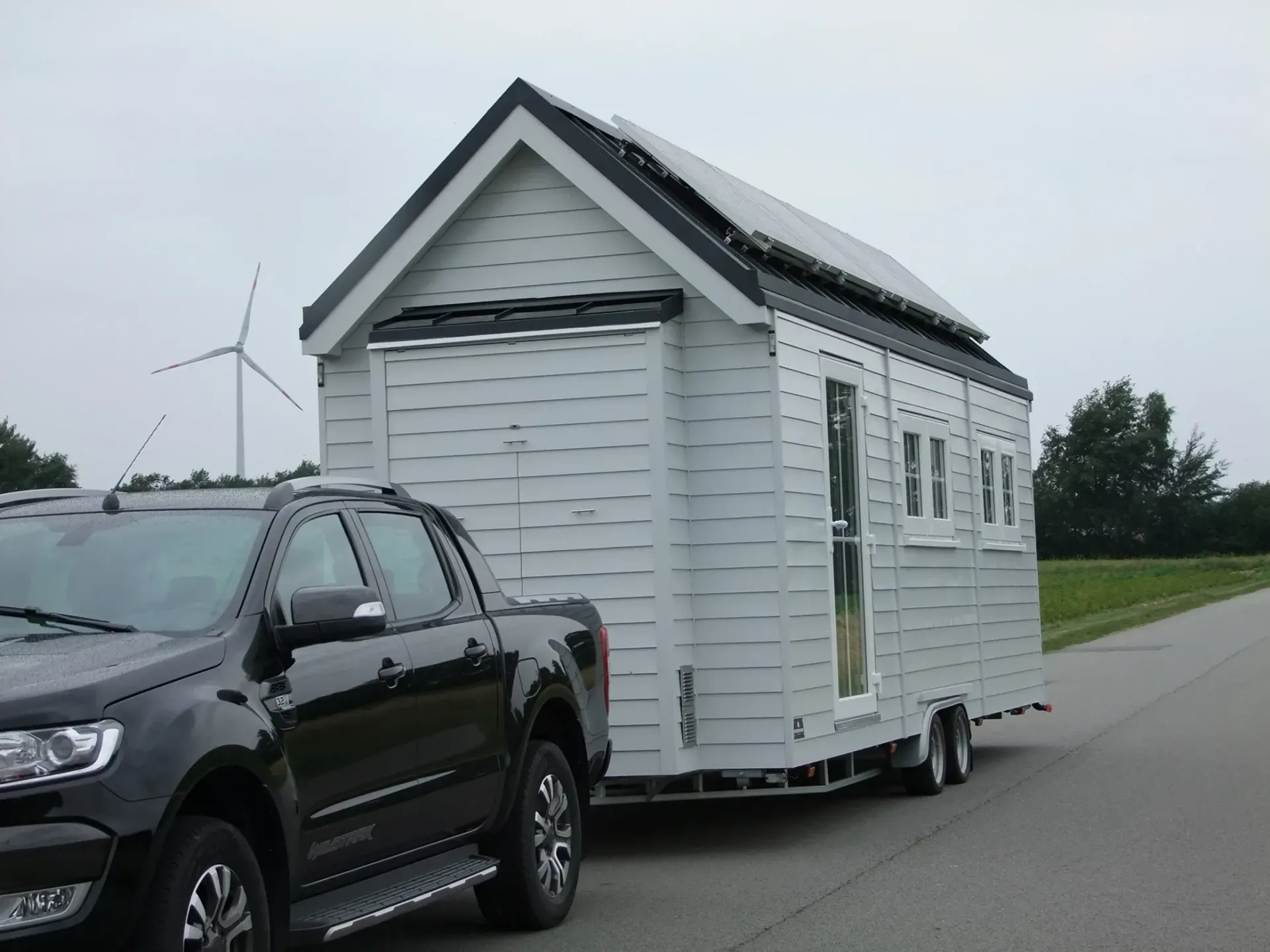 Ein schwarzer LKW zieht ein kleines weißes Haus auf einem Anhänger