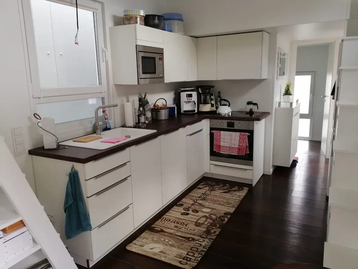 Eine Küche mit weißen Schränken und einem Teppich auf dem Boden.