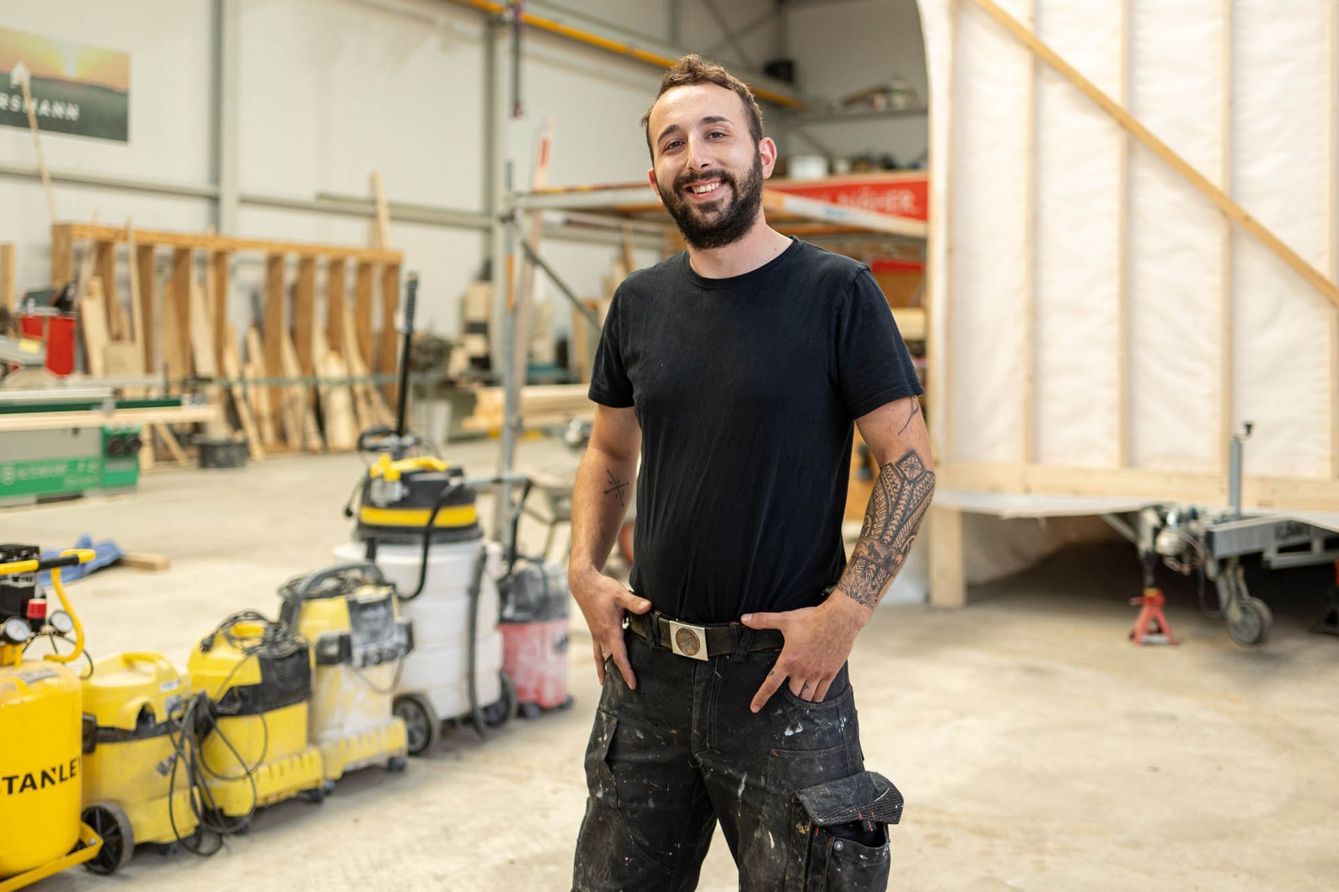 Ein Mann steht mit den Händen in den Taschen in einem Lagerhaus.