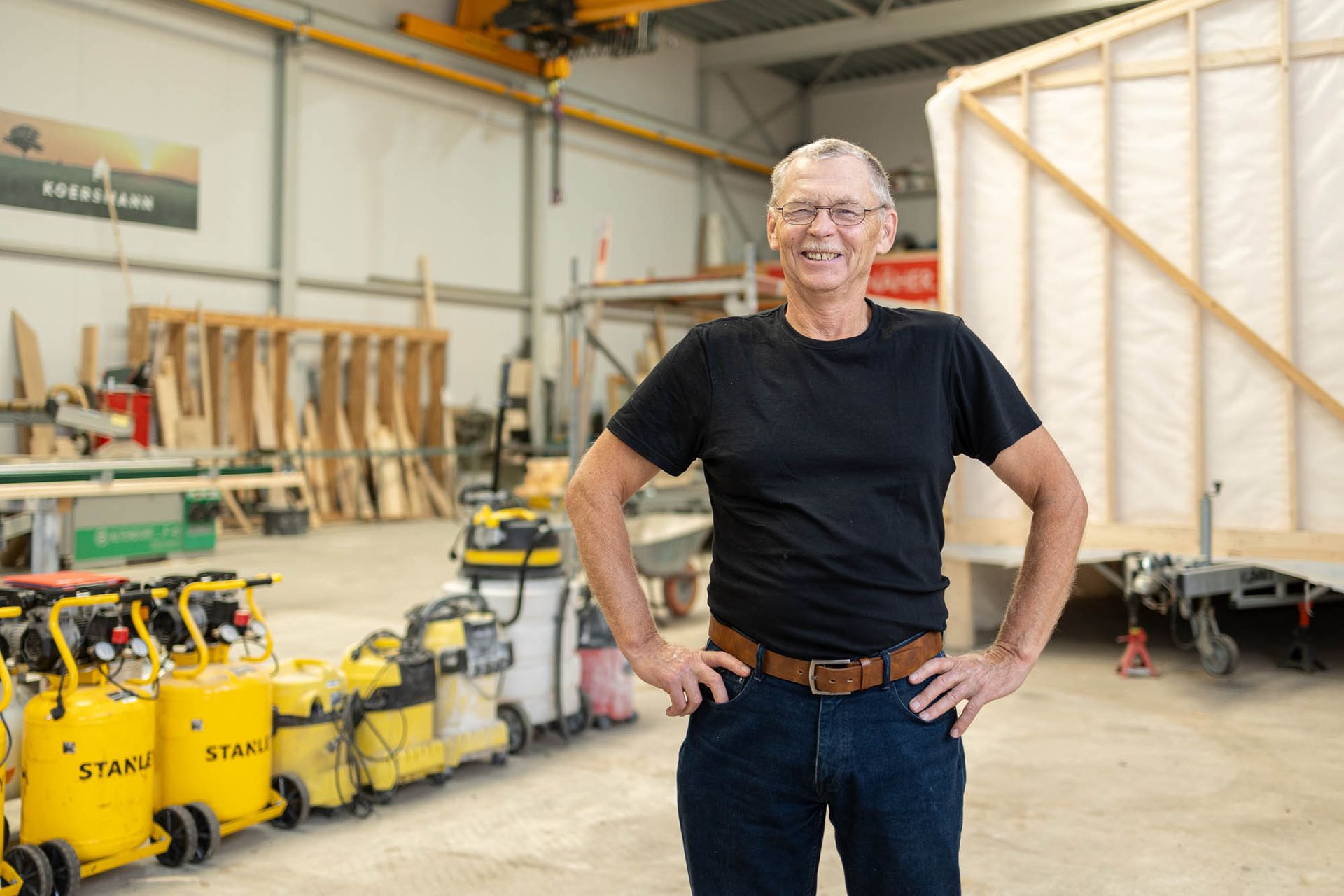 Ein Mann steht mit den Händen in den Hüften in einer Lagerhalle.
