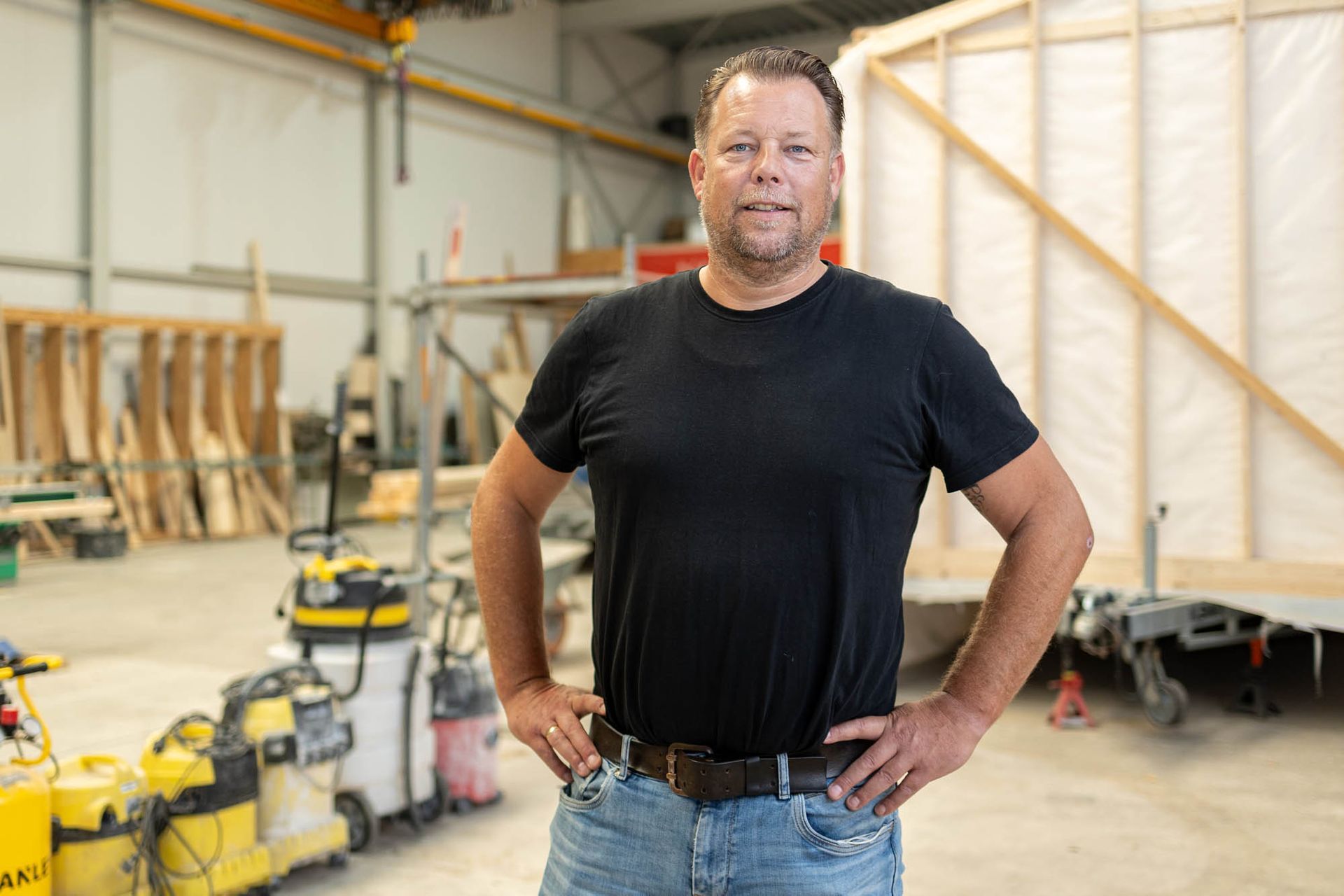 Ein Mann steht mit den Händen in den Hüften in einer Lagerhalle.