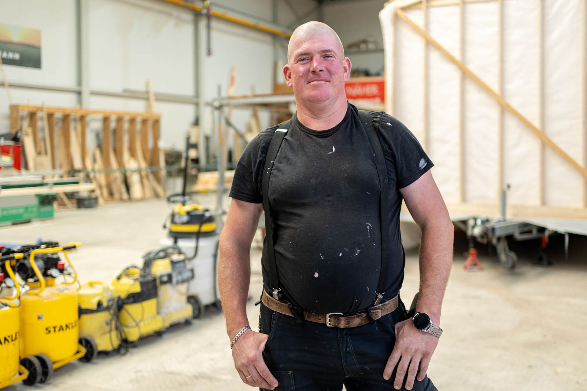 Ein Mann steht mit den Händen in den Taschen in einem Lagerhaus.