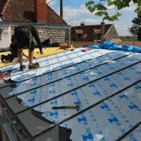 Pose d'un revêtement sur un toit par des ouvriers