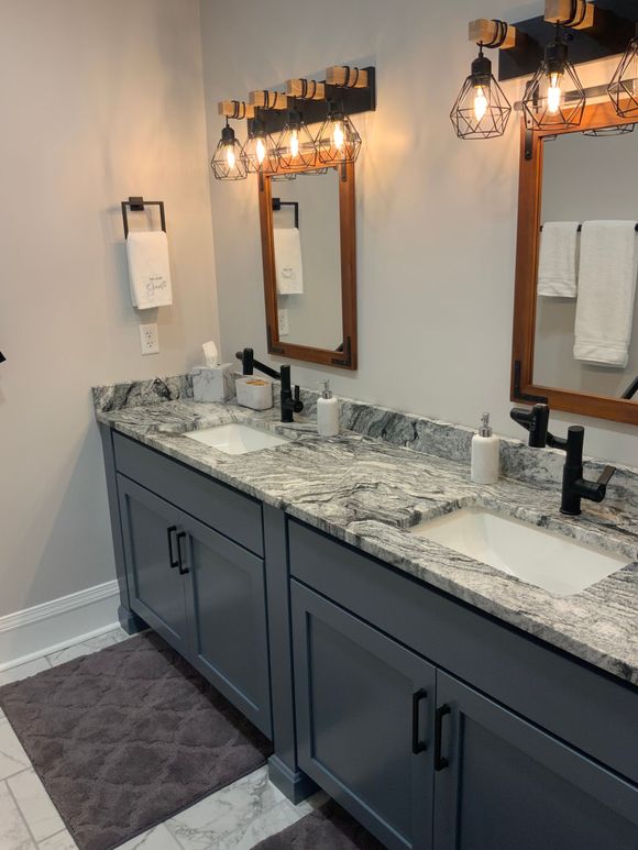 Bathroom with two sinks, gray cabinets, granite countertop, rustic mirrors, and lighting.