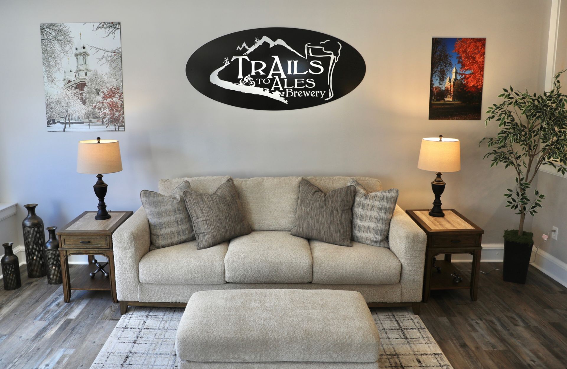 Living room with a couch, side tables, and artwork. Oval sign above couch says "Trails and Co."
