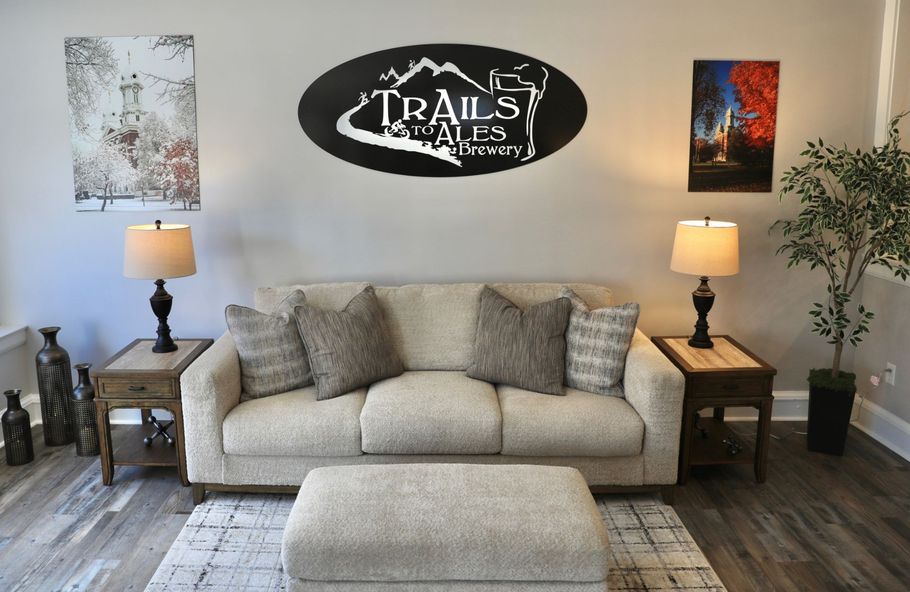Living room with a couch, lamps, and decorative art. The wall features a logo.