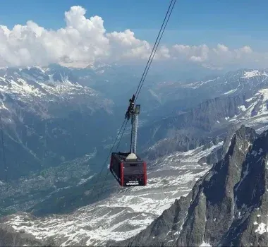 Cable car traversing between snowy mountain peaks.