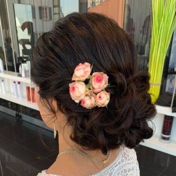 Eine Frau trägt einen Dutt mit Blumen im Haar.