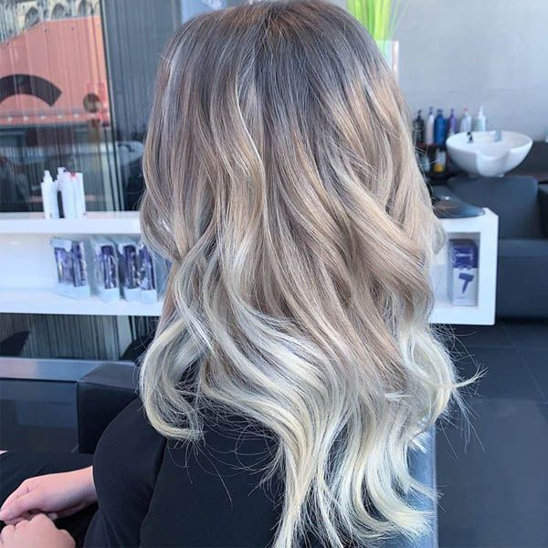 Eine Frau mit langen blonden Haaren sitzt in einem Salon.